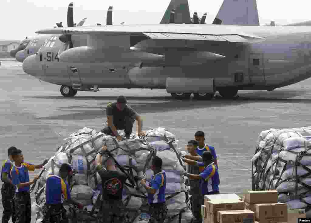 Personal militar filipino y estadounidense preparan la carga de suministros en la base aérea que trasladarán en el avión rumbo al lugar de la tragedia. 