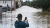 A man takes photos of a street flooded by the Opava river on September 15, 2024 in Opava, Czech Republic.