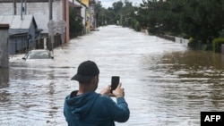 A man takes photos of a street flooded by the Opava river on September 15, 2024 in Opava, Czech Republic.