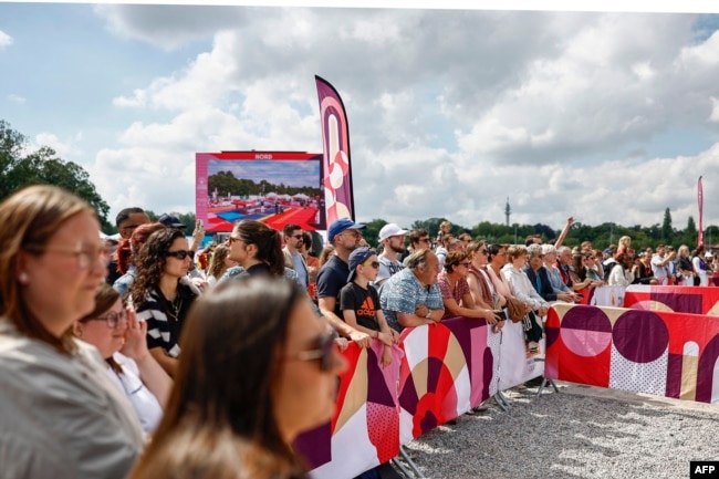 Spectators wait for the arrival of the Olympic flame as part of the Olympic torch relay at the Esplanade du Champs de Mars in Lille, northern France, on July 2, 2024, ahead of the Paris 2024 Olympic Games. (Photo by Sameer Al-Doumy / AFP)