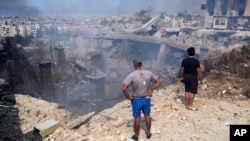 Orang-orang memeriksa bangunan yang rusak di lokasi serangan udara Israel di Choueifat, tenggara Beirut, Sabtu, 28 September 2024. (Hussein Malla/AP)