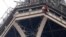 A rescue worker, top in red, hangs from the Eiffel Tower while a climber is seen below him between two iron columns Monday, May 20, 2019 in Paris. 