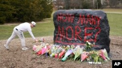 Student ostavlja cveće kod kamena na kampusu univerziteta Mičigen Stejt u Ist Lensingu. Na kamenu je ispisano "Koliko još?"