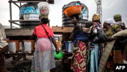 FILE - Congolese women are seen lining up to wash their hands and get their temperatures taken at a Ebola screening station on the road between Butembo and Goma, DRC, July 16, 2019. The country had declared the end of an outbreak last November. 