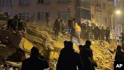 People try to reach trapped residents in a collapsed building in Pazarcik, in Kahramanmaras province, southern Turkey, early Monday, Feb. 6, 2023.