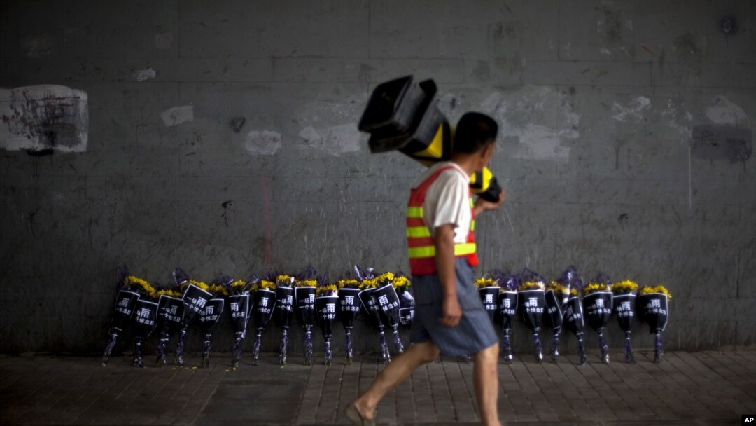 A road worker walks past flowers placed under a bridge where a man drowned July 21 in his flooded car on a main road in Beijing, July 27, 2012. 