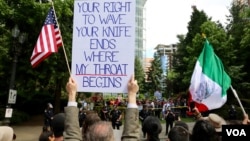 An “anti-hate” rally participant holds a sign in front of a competing “free-speech” rally across the street in downtown Portland, June 2017. (R. Taylor/VOA)