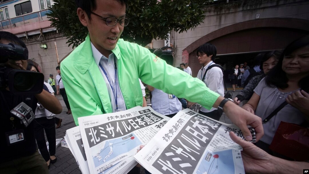 Seorang pria membagikan edisi ekstra koran yang melaporkan peluncuran misil Korea Utara di stasiun Shimbashi di Tokyo, 15 September 2017. 
