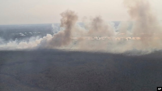 This photo released by Banjarmasin Disaster Management Agency, shows a fire that razes through a land in Banjarmasin, South Kalimantan, Indonesia, Friday, Oct. 6, 2023. (Banjarmasin Disaster Management Agency via AP)