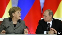 Russian President Vladimir Putin, right, and German Chancellor Angela Merkel speak to each other after a signing ceremony during a Russian-German business forum in the Grand Kremlin Palace in Moscow, Friday, Nov. 16, 2012. 