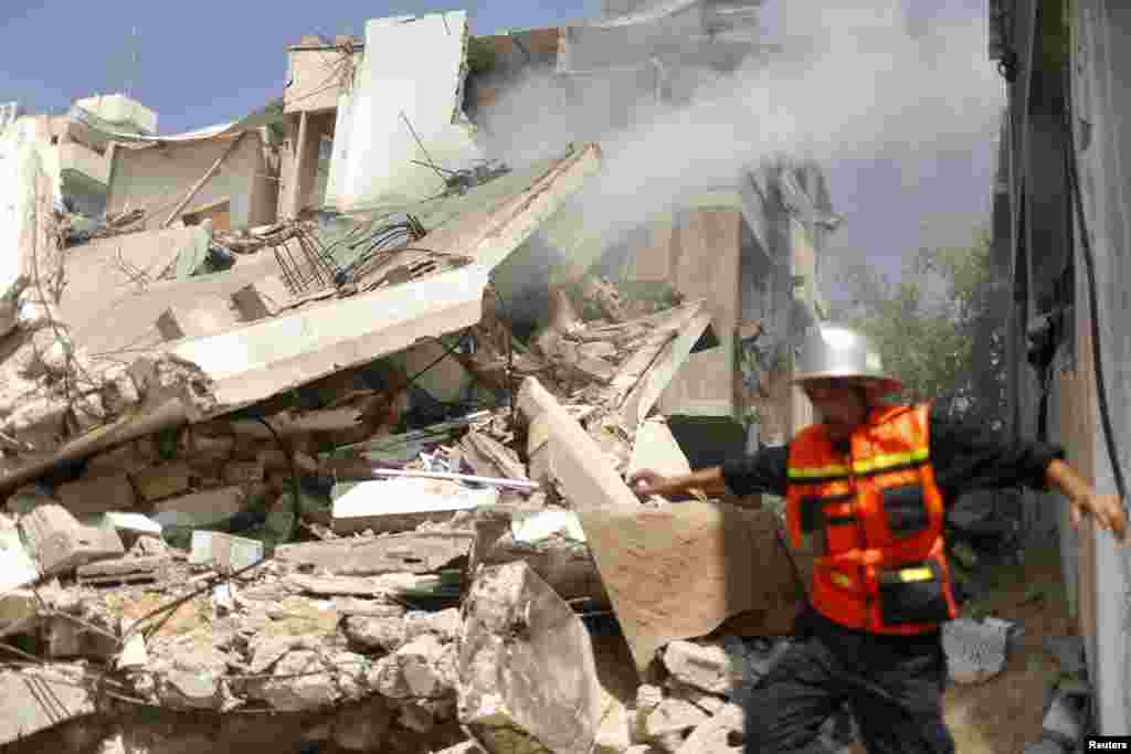 Seorang pemadam kebakaran Palestina berjalan di tengah-tengah reruntuhan sebuah rumah yang menurut para saksi terkena serangan udara Israel, Gaza City, 23 Juli 2014.