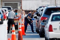 FILE - Florida Department of Health medical workers prepare to administer a COVID-19 vaccine to seniors in the parking lot of the Gulf View Square Mall in New Port Richey near Tampa, Florida, Dec. 31, 2020.