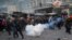 Protesters run away from a stun grenade as they clash with police in central Kyiv, Jan. 22, 2014. 