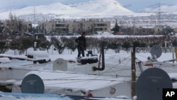 A Syrian girl stands on top of her tent to remove the snow from it at a refugee camp in Zahleh, Bekaa Valley, east Lebanon, Jan. 8, 2015.