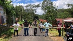 In this April 24, 2020, photo, provided by the Indigenous People Alliance of the Archipelago, indigenous peoples from the Buntao’ community in Indonesia’s North Toraja regency in South Sulawesi Province use a wooden barrier to block off their village. (AMAN via AP)