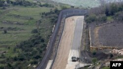 FILE - Israeli military vehicles patrol the border fence along the border with Syria, March 27, 2019. 