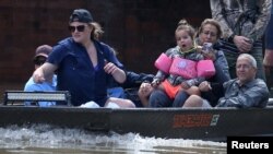 People ride a boat though flood water after being evacuated from the rising water following Hurricane Harvey in a neighborhood west of Houston, Texas, U.S., August 30, 2017.