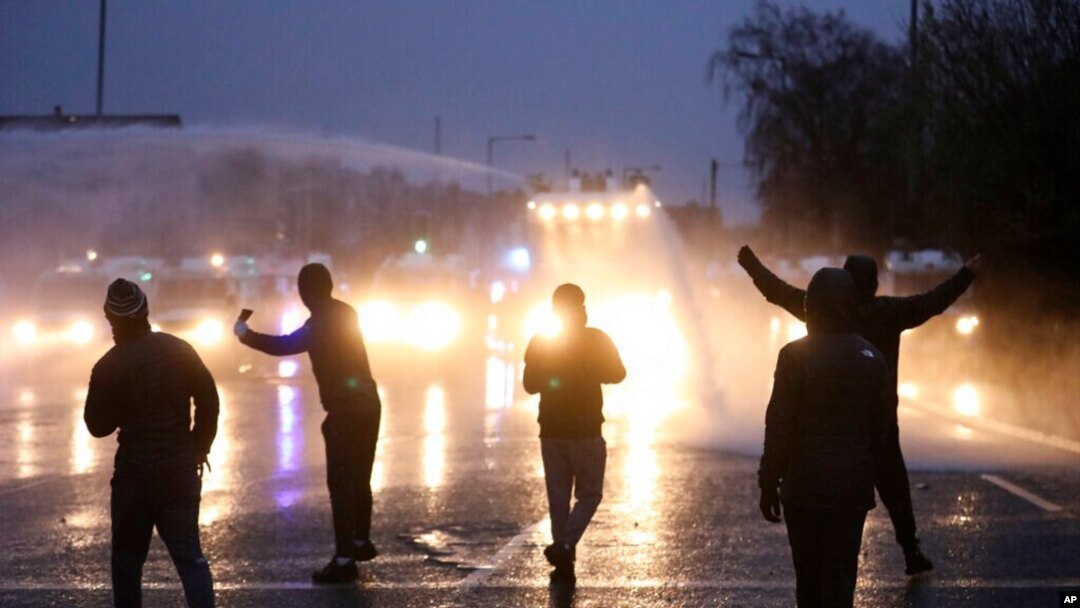 Nationalist youths gesture towards a police line blocking a road near the Peace Wall in West Belfast, Northern Ireland, April 8, 2021.