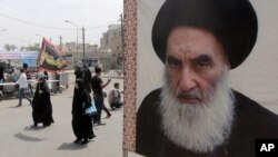 Peziarah Syi'ah berjalan menuju kuil Imam Moussa al-Kadhim, melewati poster pemimpin spiritual Syiah Ayatollah Ali al-Sistani (kanan), di Baghdad, Irak, 22 Mei 2014. (Foto: dok).