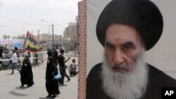 FILE - Shii'te pilgrims make their way to the shrine of Imam Moussa al-Kadhim as passing by a poster of Shi'ite spiritual leader Grand Ayatollah Ali al-Sistani, right, in Baghdad, Iraq.