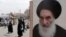 FILE - Shii'te pilgrims make their way to the shrine of Imam Moussa al-Kadhim as passing by a poster of Shi'ite spiritual leader Grand Ayatollah Ali al-Sistani, right, in Baghdad, Iraq.