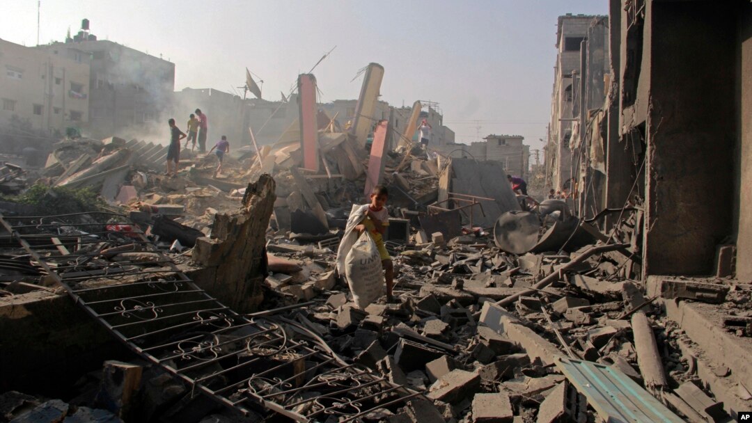 Warga Palestina mencari barang-barangnya di antara reruntuhan gedung di Rafah, Jalur Gaza.