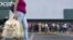 FILE - A woman carries bags with toilet paper rolls as people line up to buy staple items at a Makro supermarket in Caracas Aug. 4, 2015.