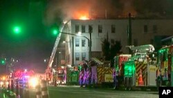 In this image made from video, firetrucks stage outside a hostel in central Wellington, New Zealand, May 16, 2023. Several people were killed after a fire broke out overnight at the four-story building.