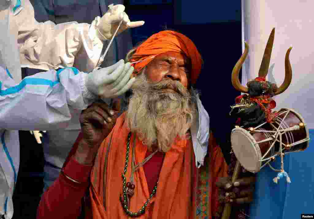 A Hindu holy man, or Sadhu, reacts as a health care worker collects a swab sample for a COVID-19 test at a base camp where pilgrims gather before heading for an annual trip to Sagar Island for the one-day festival of Makar Sankranti, in Kolkata, India.