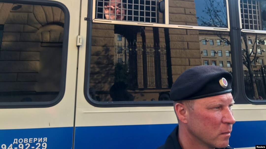 Arhiv - Policajac stoji ispred autobusa sa novinarima uhapšenim tokom mitinga u Moskvi, 7. jula 2019.