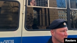 Arhiv - Policajac stoji ispred autobusa sa novinarima uhapšenim tokom mitinga u Moskvi, 7. jula 2019.