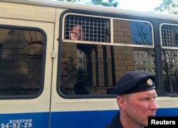 FILE - A police officer stands in front of a bus with reporters detained after a rally in Moscow, Russia, June 7, 2019.