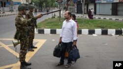 Seorang tentara pasukan militer Bangladesh meminta pasangan tersebut untuk kembali ke rumahnya di Dhaka, Bangladesh, Sabtu, 20 Juli 2024. (Foto: AP)