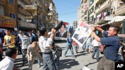 A protester uses a shoe to beat a picture of Syria's President Bashar al-Assad during a protest organized by Lebanese and Syrians living in Lebanon, in solidarity with Syria's anti-government protesters, in the port-city of Tripoli, northern Lebanon, Octo