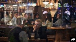 FILE - People sit in a bar in Stockholm, Sweden, on March 25, 2020. Sweden wants to cut red tape when it comes to dancing. (AP Photo/David Keyton, File)