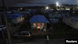 A house is lit up with the help of a generator next to houses in the dark after Hurricane Maria damaged the electrical grid in September, in Dorado, Puerto Rico Jan. 15, 2018. 