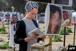 FILE — A woman reads at the site of the Supernova music festival in southern Israel as supporters of Israeli hostages held in Gaza since the October 7 attacks by Hamas militants, start of a four-day march to Jerusalem calling for their release, on February 28, 2024.