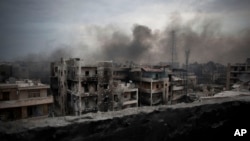 FILE - Smoke is seen rising over Saif Al Dawla district, in Aleppo, Syria.