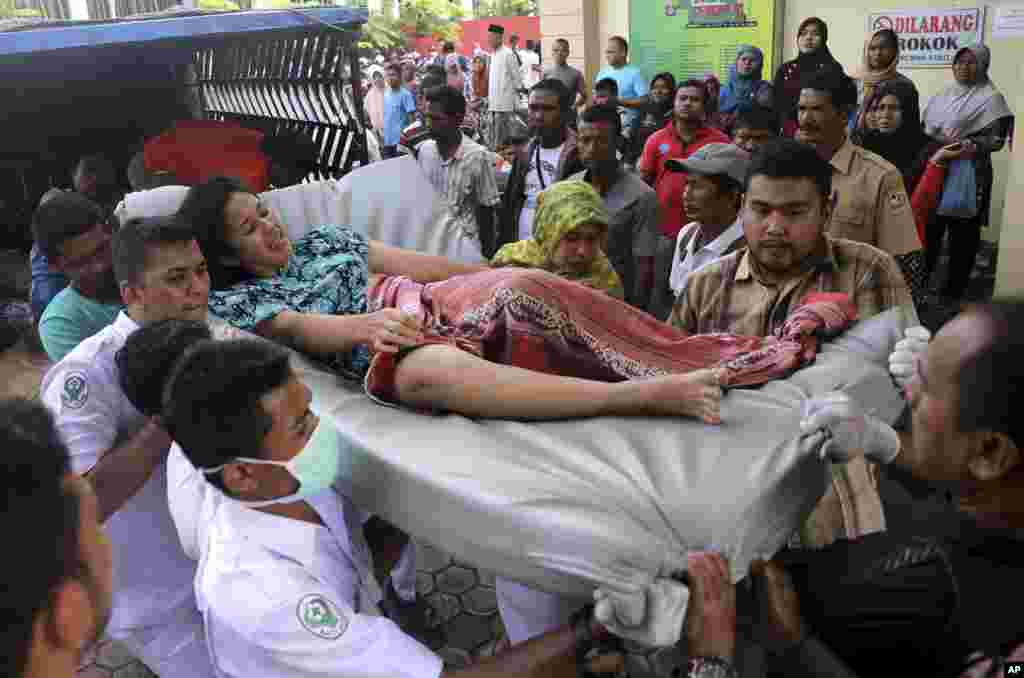 Petugas rumah sakit dan anggota keluarga menggotong perempuan yang terluka dalam gempa bumi di Pidie Jaya, Aceh (7/12). (AP/Heri Juanda)