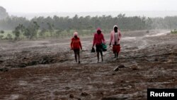 Residents walk in the rain at the Solai farm after their dam burst its walls, overrunning nearby homes, in Solai town near Nakuru, Kenya, May 10, 2018. 