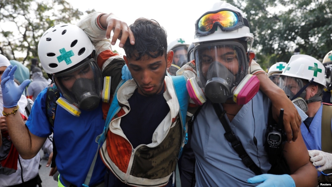 Para relawan menolong pengunjuk rasa yang terluka (tengah) saat melakukan aksi demo menentang Presiden Nicolas Maduro di Caracas, Venezuela, 24 April 2017. (REUTERS/Carlos Garcia Rawlins).