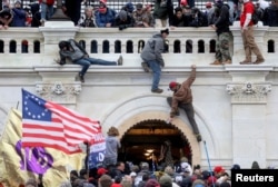 FILE - A mob of supporters of U.S. President Donald Trump fight with members of law enforcement at a door they broke open as they storm the U.S. Capitol building in Washington, Jan. 6, 2021.