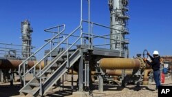 FILE - A worker operates valves in West Qurna oil field near the city of Basra, 340 miles (550 kilometers) southeast of Baghdad, Iraq, Feb. 21, 2017. 