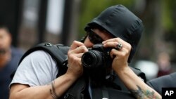 Seorang fotografer mengenakan helm pelindung mengabadikan peristiwa unjuk rasa menentang pembunuhan dan penghilangan sejumlah wartawan di Mexico City, Meksiko, 21 Agustus 2019.(Foto: AP)