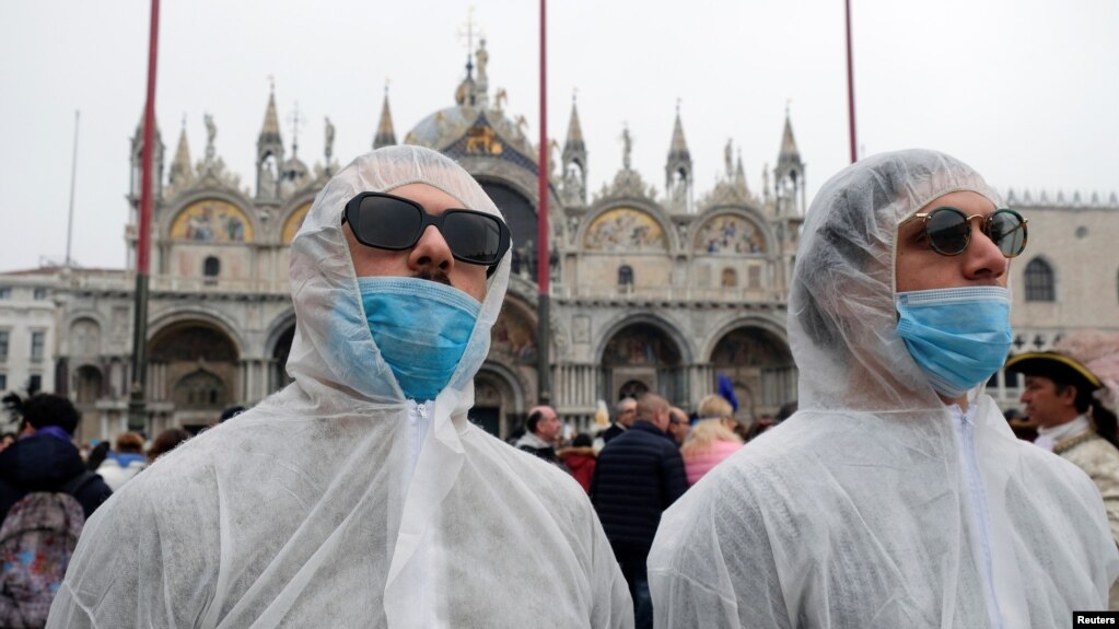 Tourists wear protective face masks at Venice Carnival, which the last two days of, as well as Sunday night's festivities, have been cancelled because of an outbreak of coronavirus, in Venice, Italy February 23, 2020. REUTERS/Manuel Silvestri