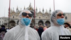 Tourists wear protective face masks at Venice Carnival, which the last two days of, as well as Sunday night's festivities, have been cancelled because of an outbreak of coronavirus, in Venice, Italy February 23, 2020. REUTERS/Manuel Silvestri