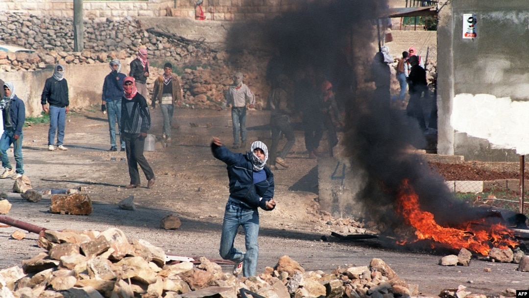 FILE - Palestinian rioters throw stones at Israeli riot police in North Jerusalem village of Hizme, Dec. 21, 1987.
