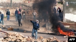 FILE - Palestinian rioters throw stones at Israeli riot police in North Jerusalem village of Hizme, Dec. 21, 1987.