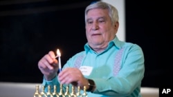 Rabbi Peter Tarlow lights a candle on a menorah during a Chicanukah event at the Holocaust Museum Houston, in Houston, Texas, Dec. 19, 2024.