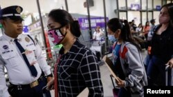 Pekerja Filipina Rantau (OFW) yang mengenakan masker pelindung berjalan menuju pintu masuk keberangkatan Bandara Internasional Ninoy Aquino di Pasay City, Metro Manila, Filipina, 18 Februari 2020. (Foto: REUTERS/Eloisa Lope)